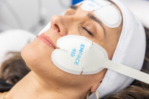 A woman reclines and smiles while she receives Emface for skin rejuvenation in Thunder Bay, ON.