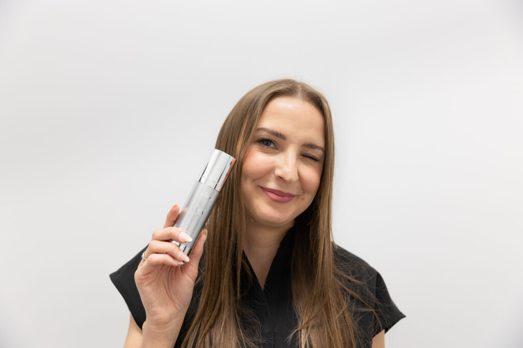 A provider smiles and holds up one of our skin care products in Thunder Bay, ON